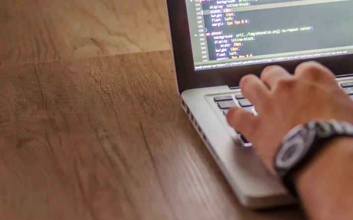 Developer typing code on a laptop to add the Preferred Sources button to a WordPress site without a plugin
