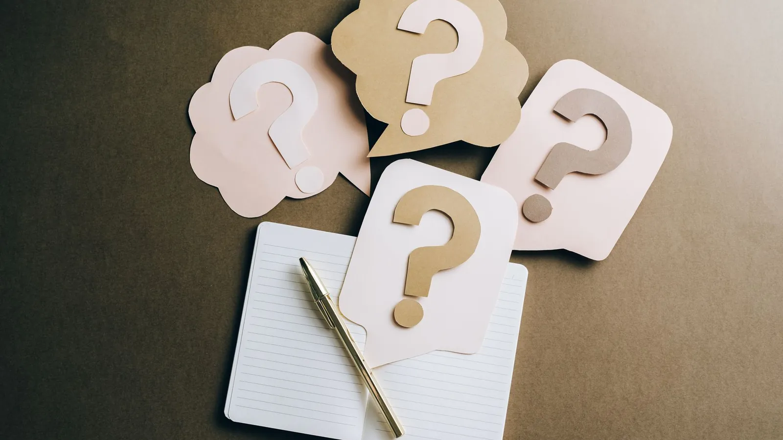 Paper question mark cards on a notebook, representing FAQ schema questions in Google Search