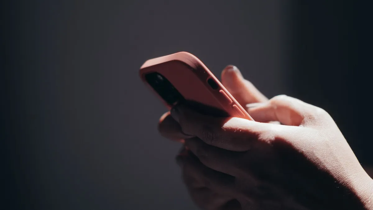 Hands holding a phone in low light, checking an Instagram account that follows people by itself