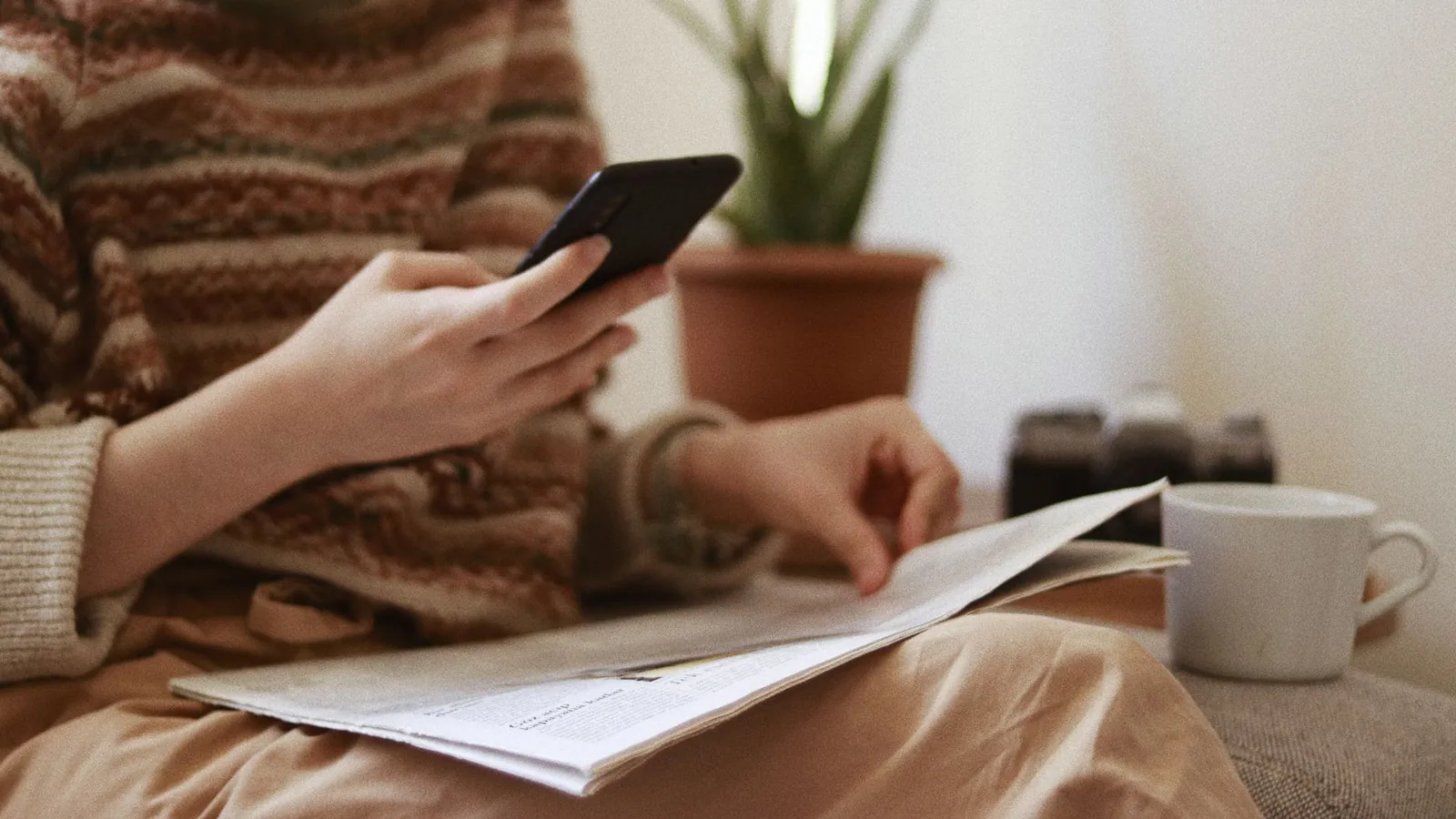 Reader checking news on a smartphone next to a newspaper, the audience a Search Profile badge or Preferred Sources button reaches