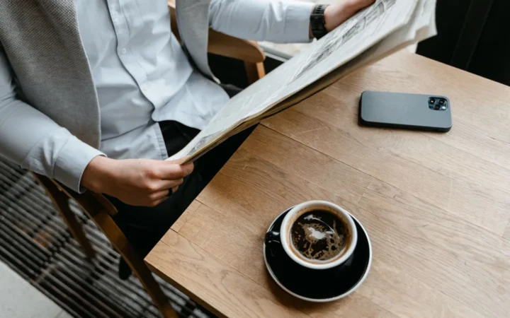 Person reading the news with coffee and a phone, the reader who picks preferred sources in Google