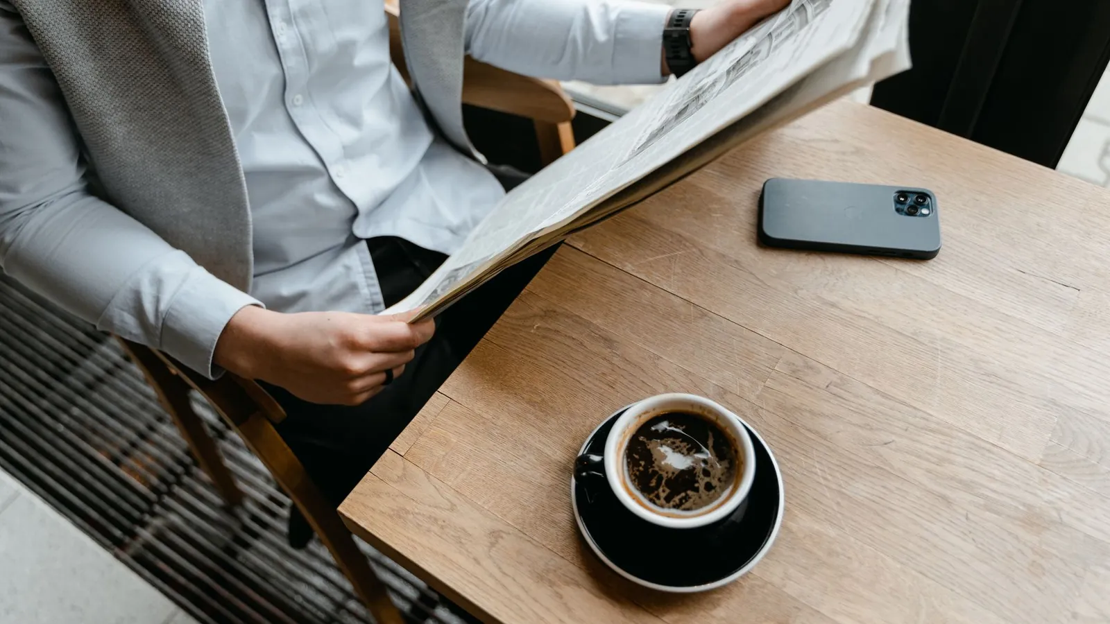 Person reading the news with coffee and a phone, the reader who picks preferred sources in Google